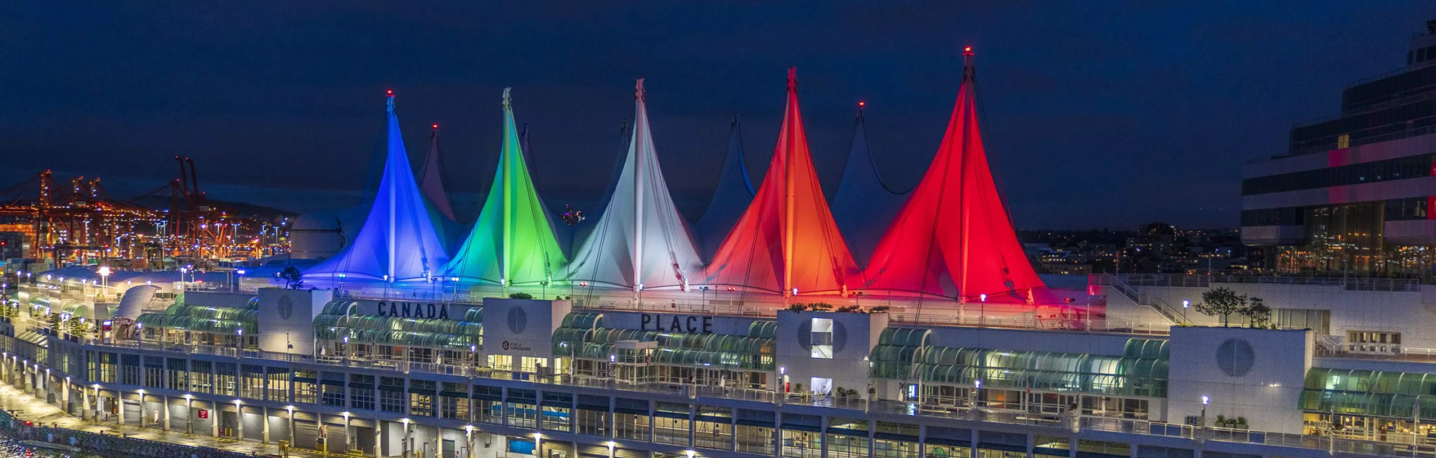 Photo of Canada Place's sails illuminated in multiple colours