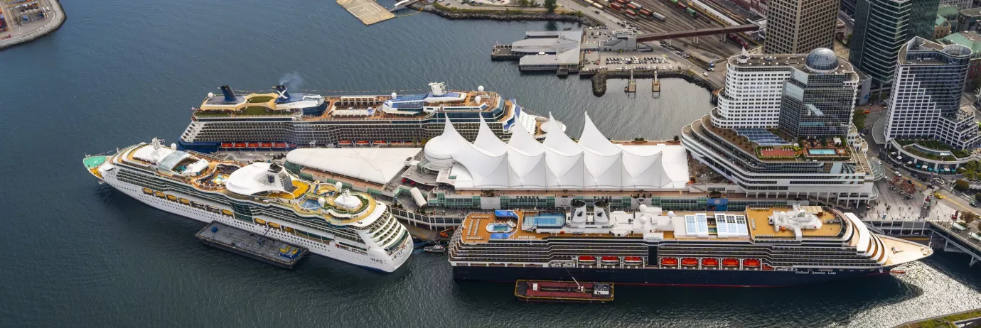 Three cruise ships are berthed around the Canada Place cruise terminal, seen from above